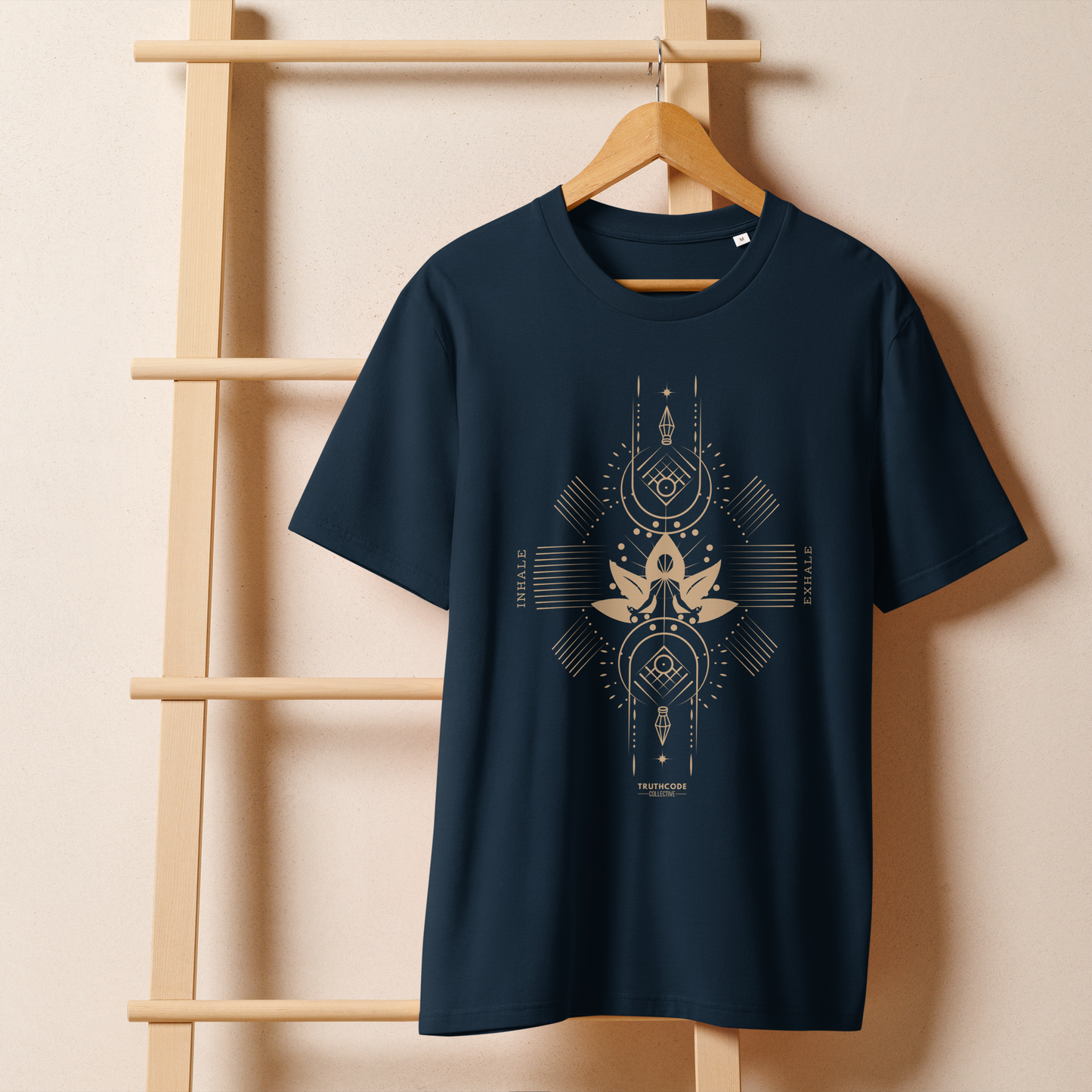 Navy blue organic t-shirt with geometric design, lotus flower and meditating person, with text reading 'Inhale, exhale' hanging on a wooden hanger