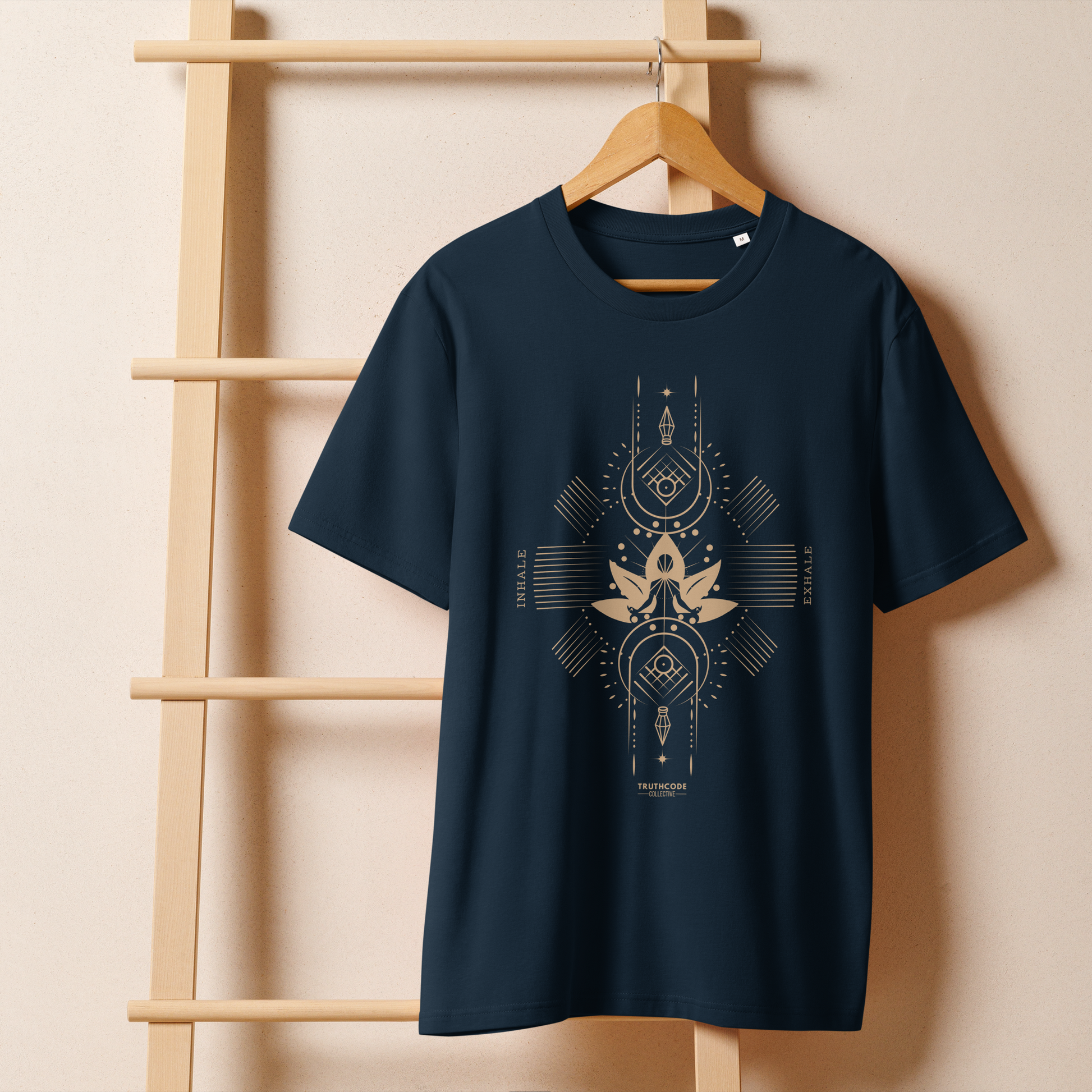 Navy blue organic t-shirt with geometric design, lotus flower and meditating person, with text reading 'Inhale, exhale' hanging on a wooden hanger