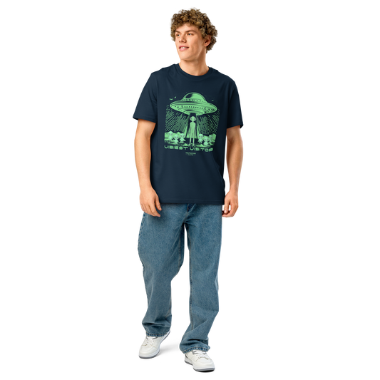 Guy wearing navy blue organic t-shirt with green alien and UFO graphic and text 'Vibiest visitors' on a white background