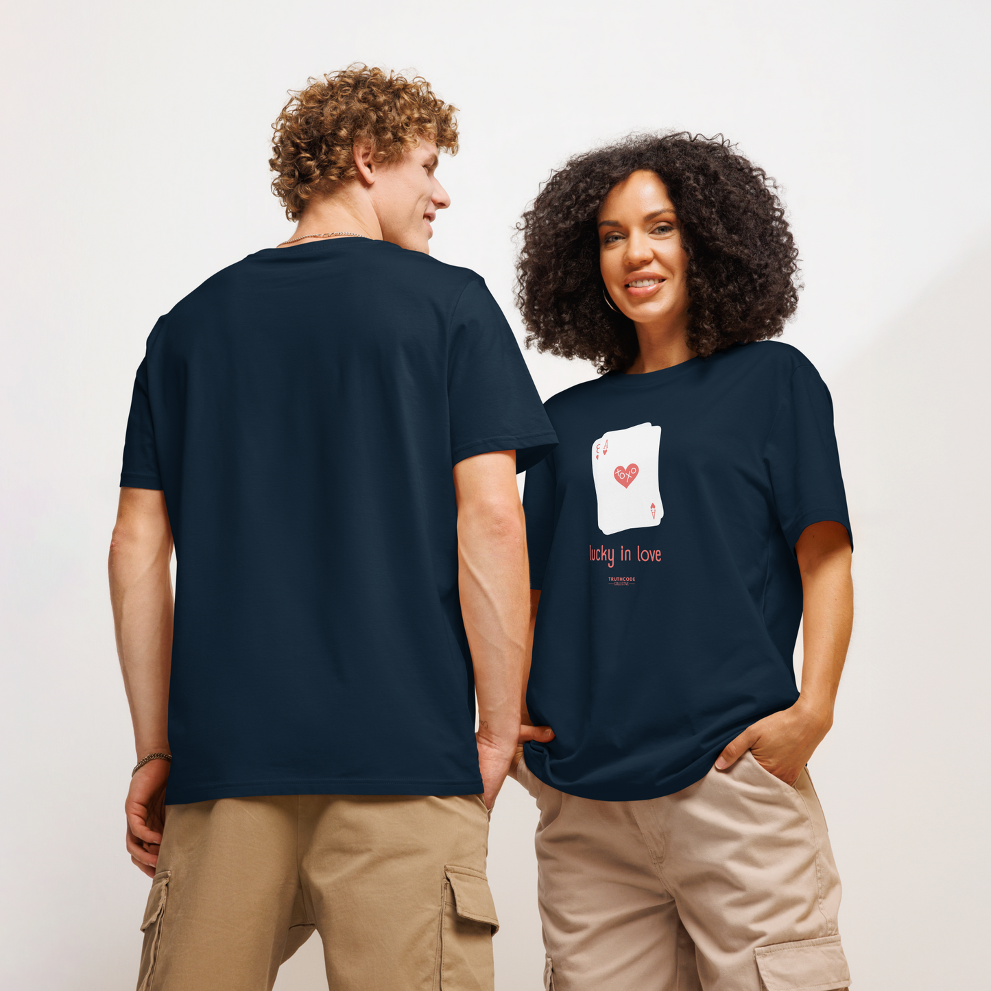 Models wearing navy blue organic t-shirt with a graphic of playing cards and 'lucky in love' text on a white background