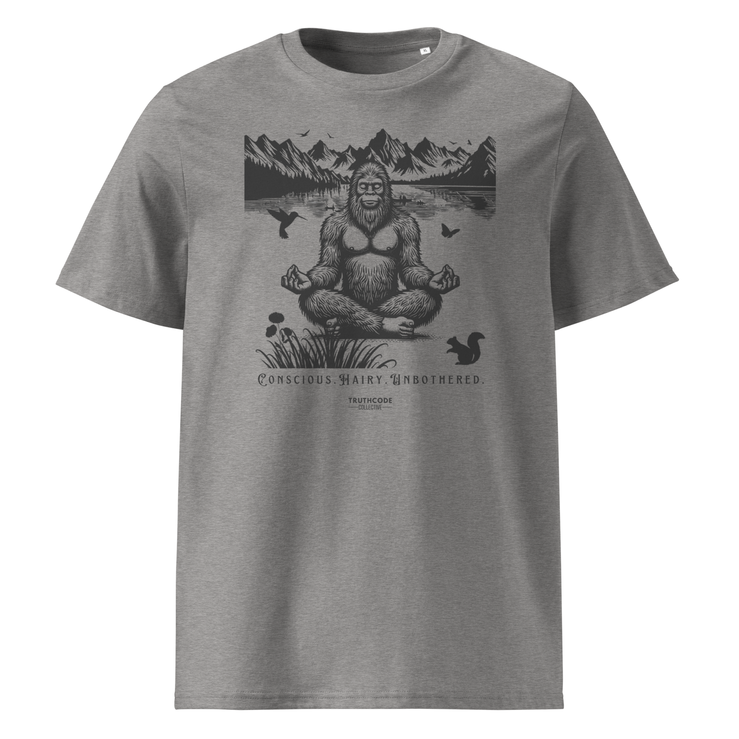 Gray organic t-shirt with a graphic of a meditating Sasquatch in a mountain setting and text reading 'Conscious, hairy, and unbothered' 
