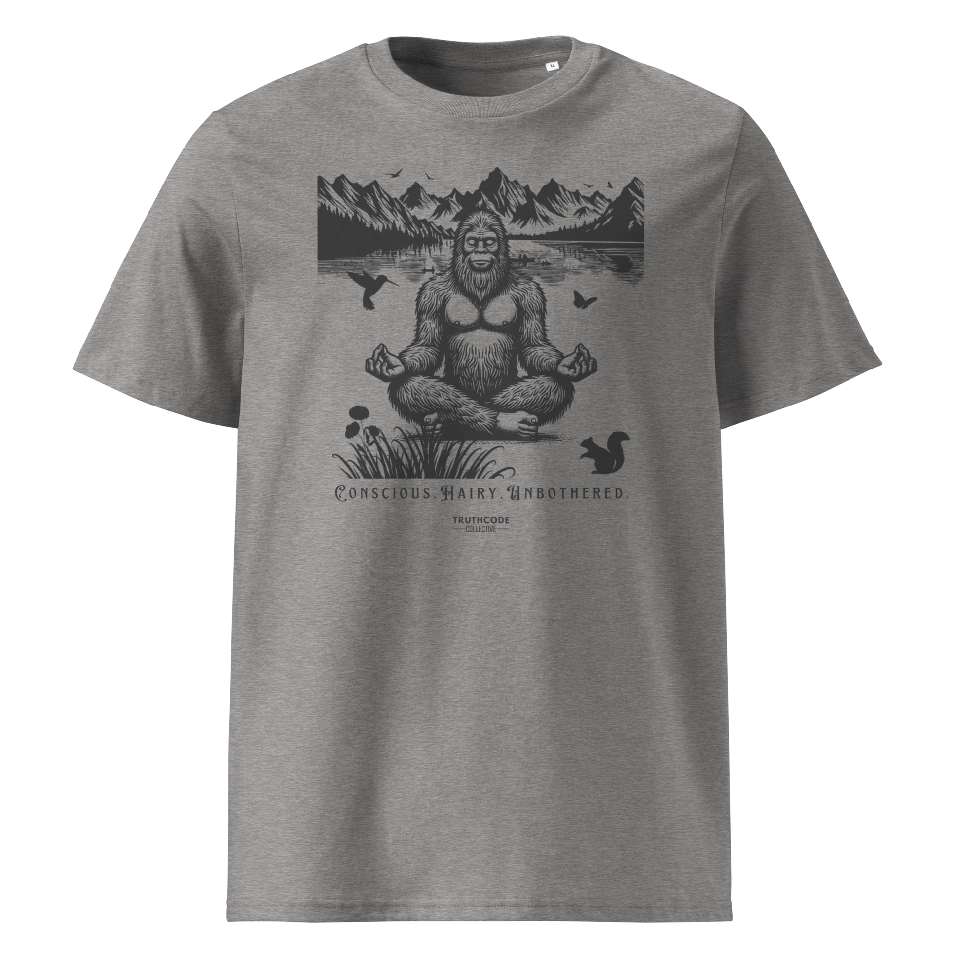 Gray organic t-shirt with a graphic of a meditating Sasquatch in a mountain setting and text reading 'Conscious, hairy, and unbothered' 
