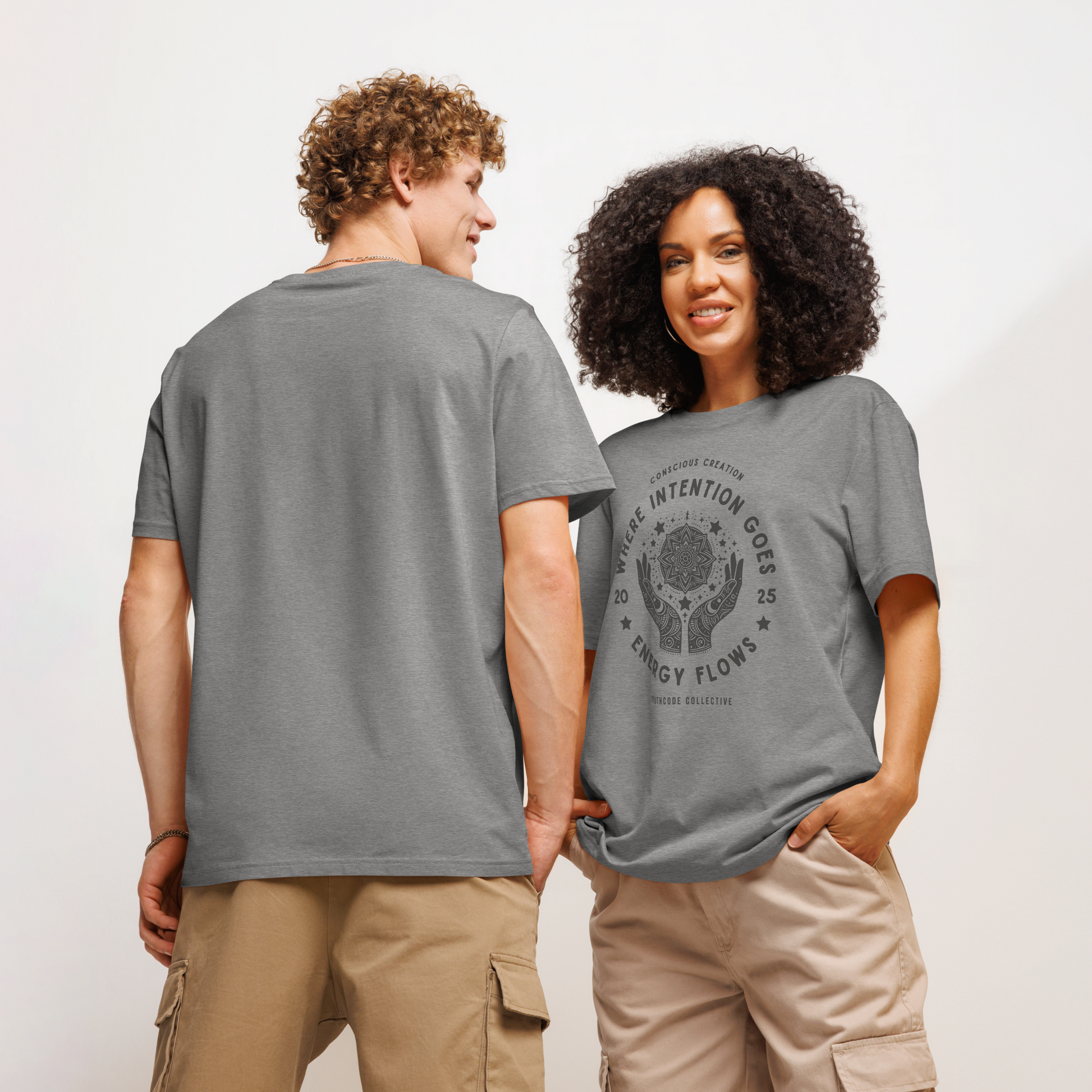 Models wearing gray organic t-shirt with graphic design of hands around a mandala and text 'Where intention goes energy flows' on a white background