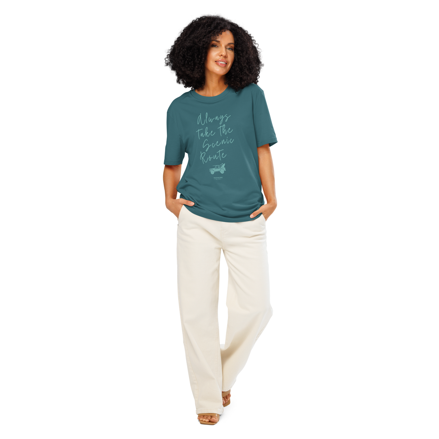 Woman wearing teal organic t-shirt with text design 'Always take the scenic route' with truck with surf board graphic on a white background