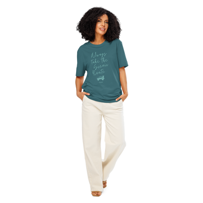 Woman wearing teal organic t-shirt with text design 'Always take the scenic route' with truck with surf board graphic on a white background
