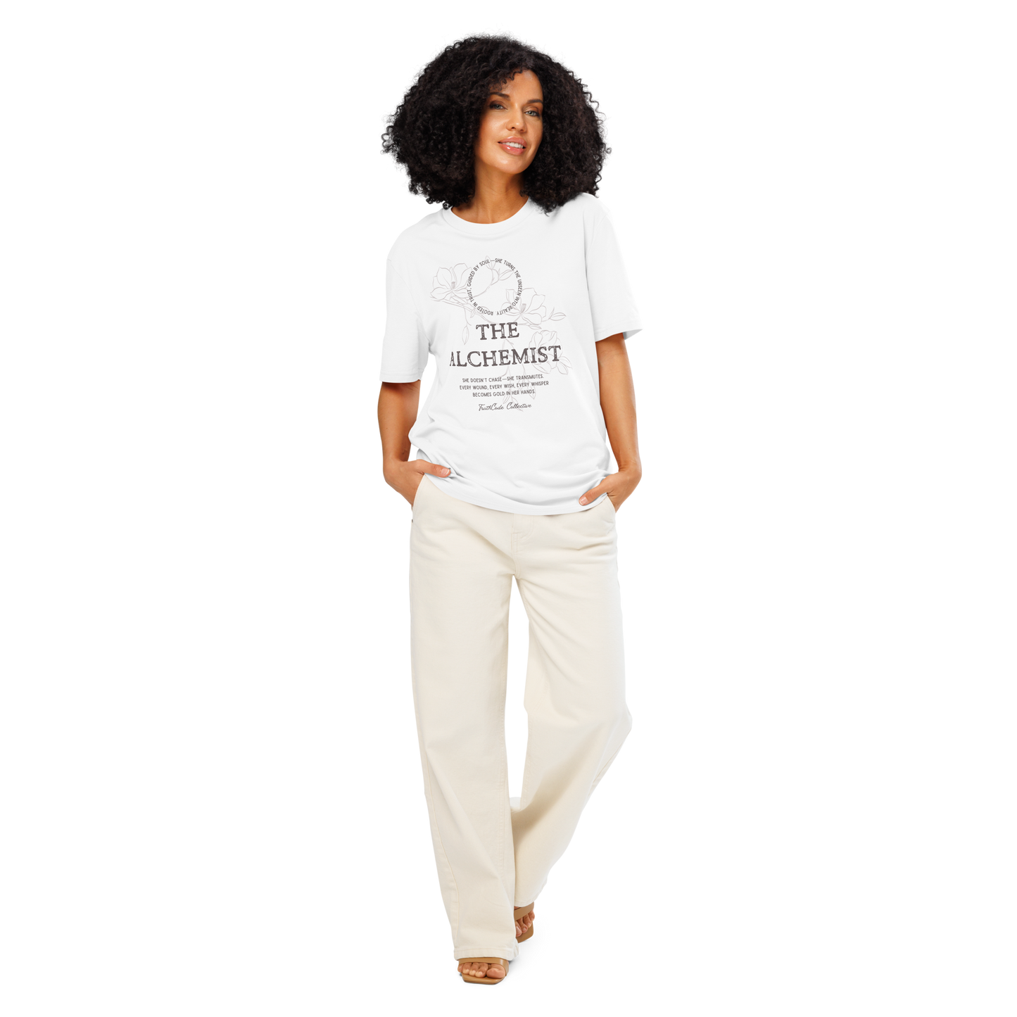 Woman wearing white organic t-shirt with text 'The Alchemist, she doesn't chase- she transmutes...' and subtle floral background design