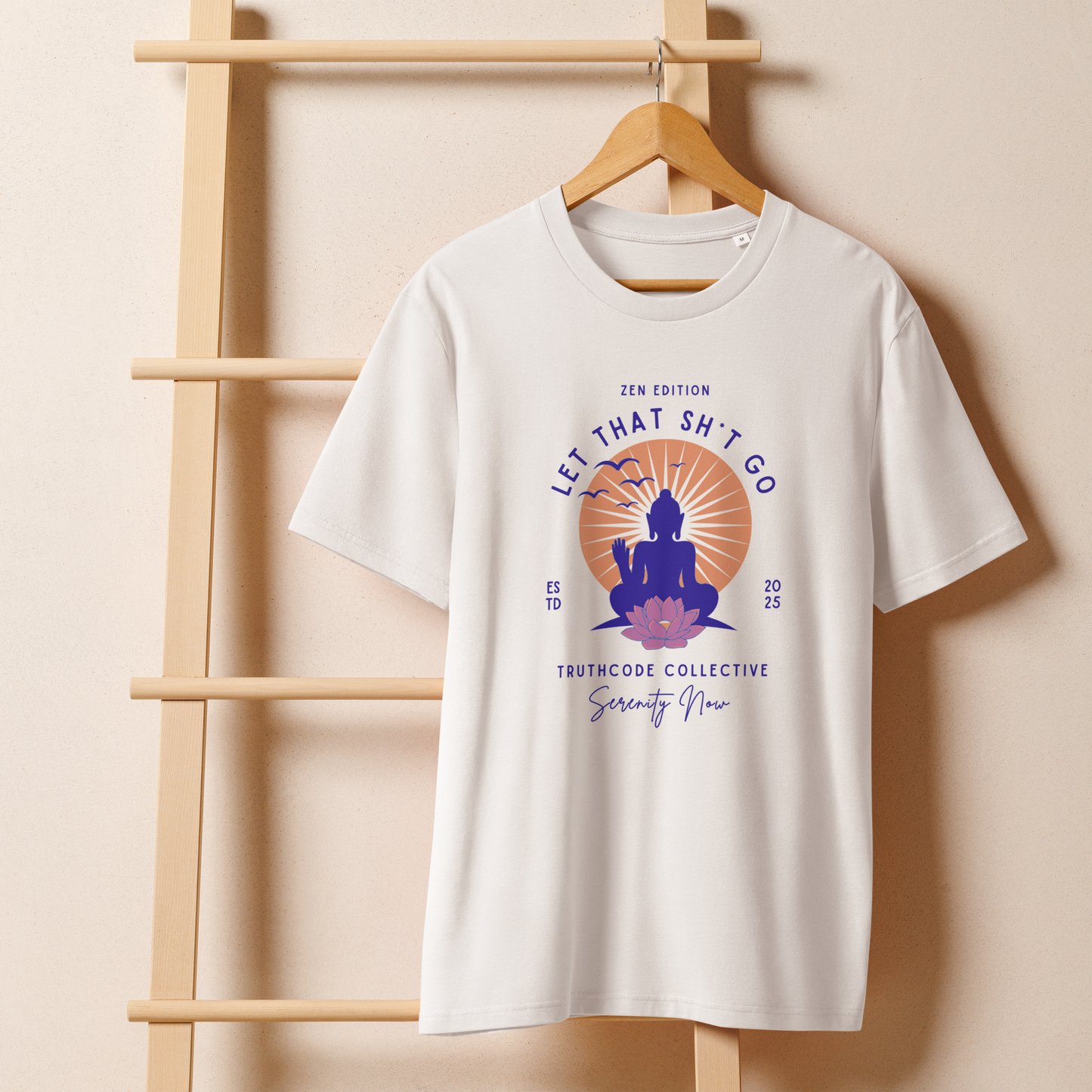 White organic t-shirt with a Buddha graphic and text 'Let that sh*t go' on a wooden hanger with a beige wall background