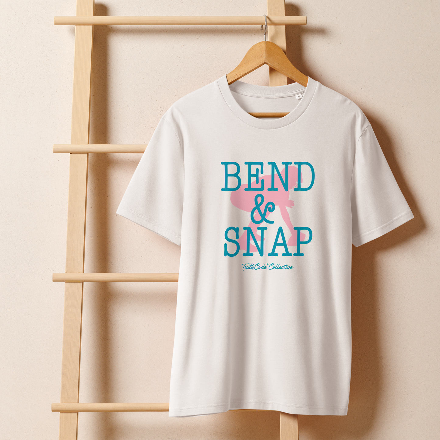 White organic t-shirt with 'Bend & Snap' text and football center graphic design, shirt is on a wooden hanger with a beige wall background