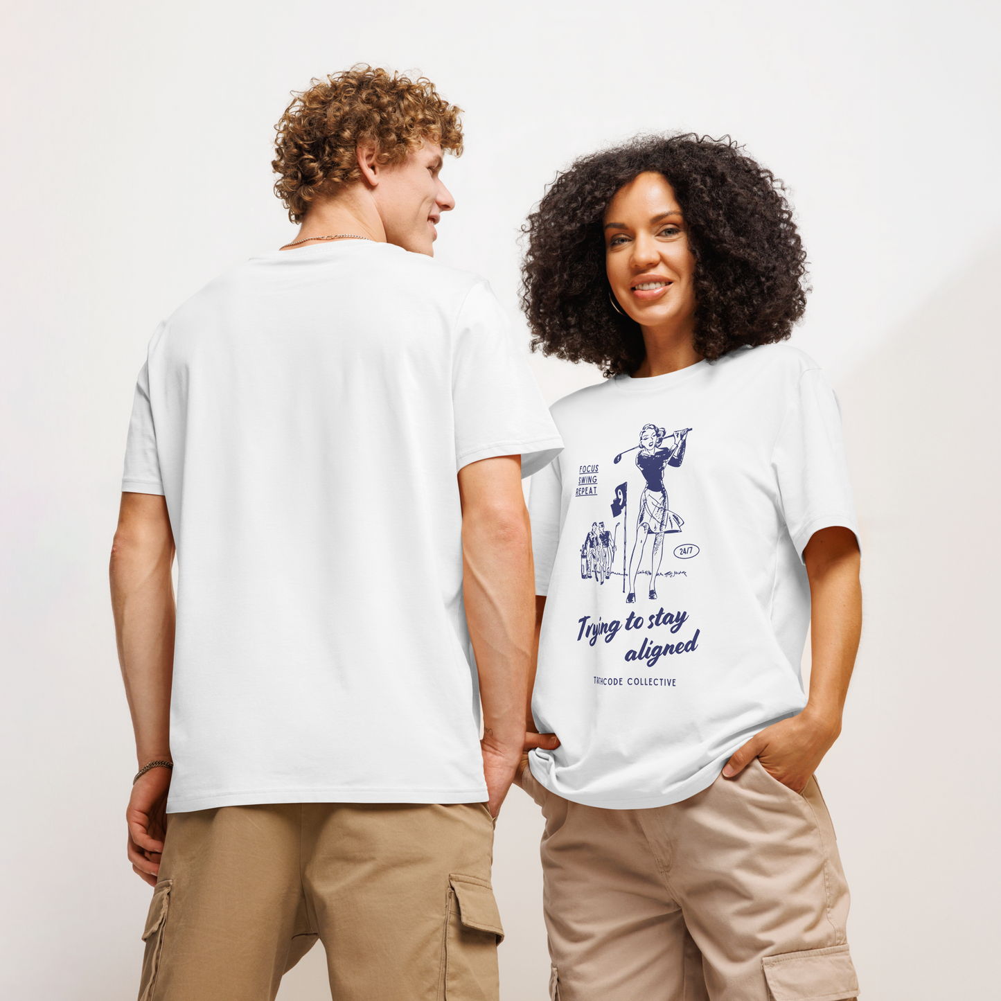 Models wearing white organic t-shirt with blue vintage graphic of a woman golfing and text 'Trying to stay aligned' and 'Focus, swing, repeat' on a white background