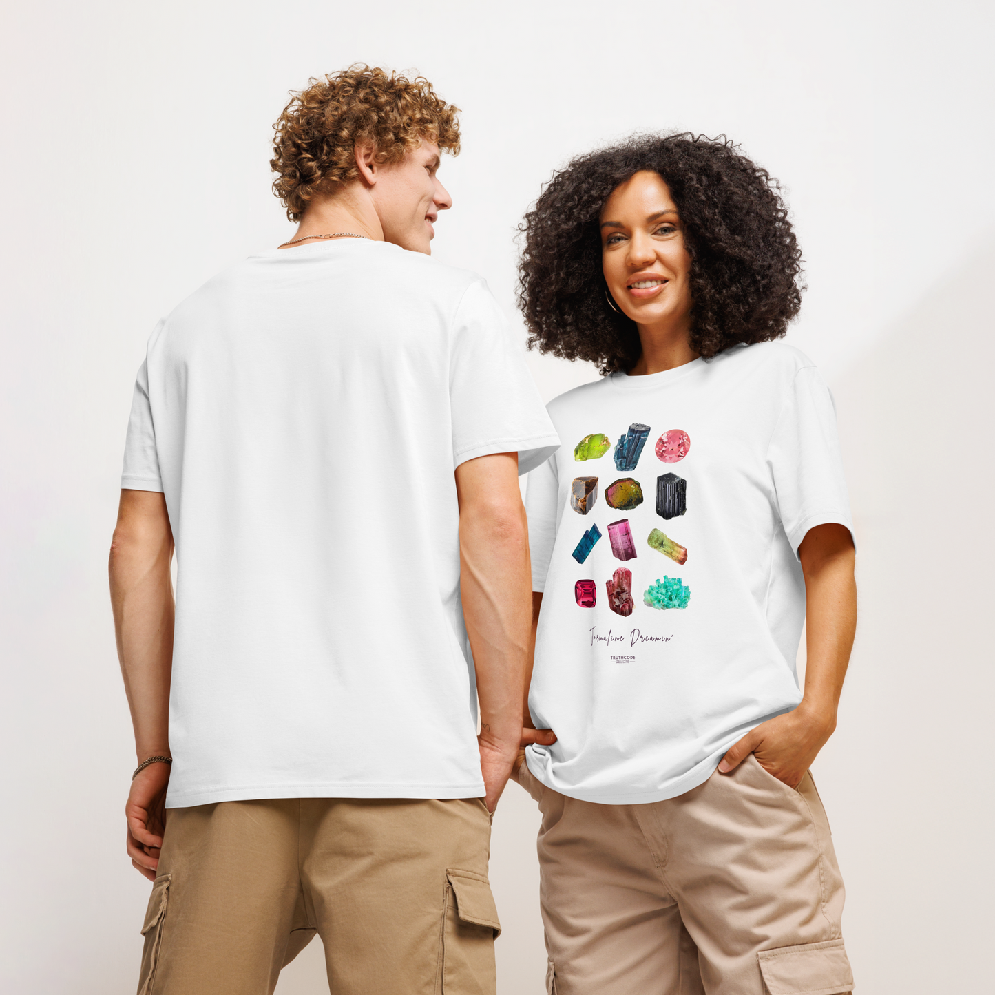 Models wearing white organic t-shirt with colorful gemstone designs and text 'Tourmaline Dreamin' on a plain background
