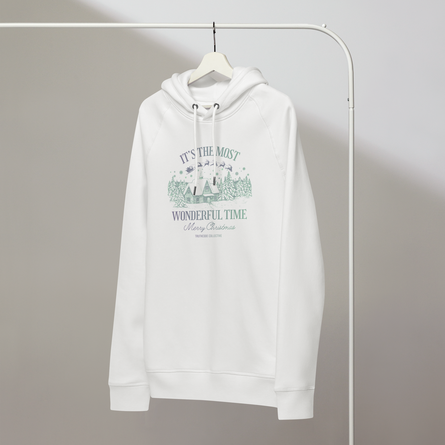 White organic hoodie with Christmas-themed design and text 'It's the most wonderful time of the year' on a hanger with a gray wall background