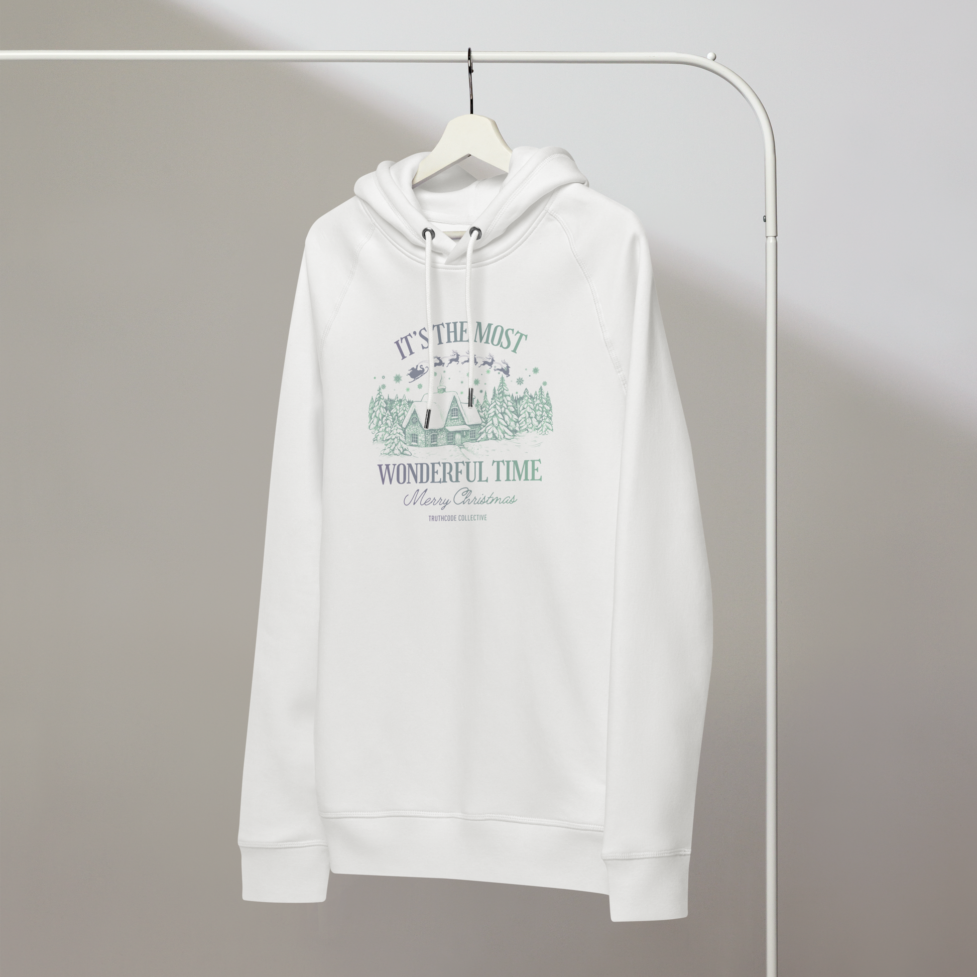 White organic hoodie with Christmas-themed design and text 'It's the most wonderful time of the year' on a hanger with a gray wall background